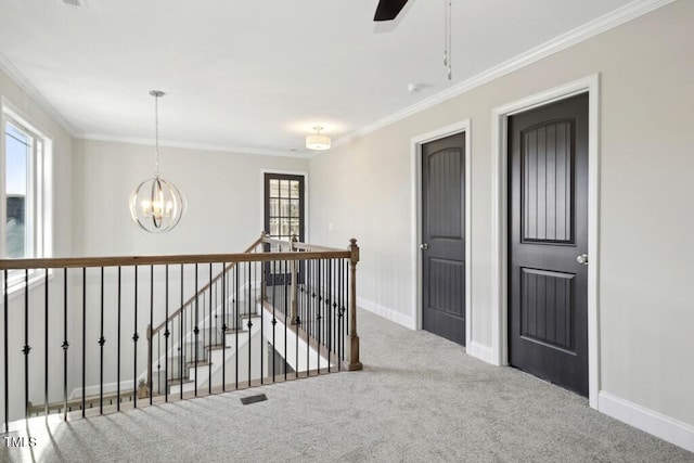 hallway featuring an inviting chandelier, ornamental molding, and carpet floors