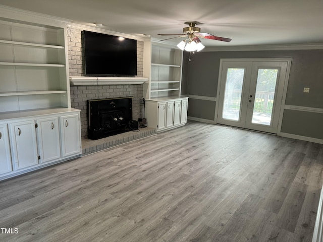 unfurnished living room featuring built in shelves, ceiling fan, french doors, crown molding, and light wood-type flooring