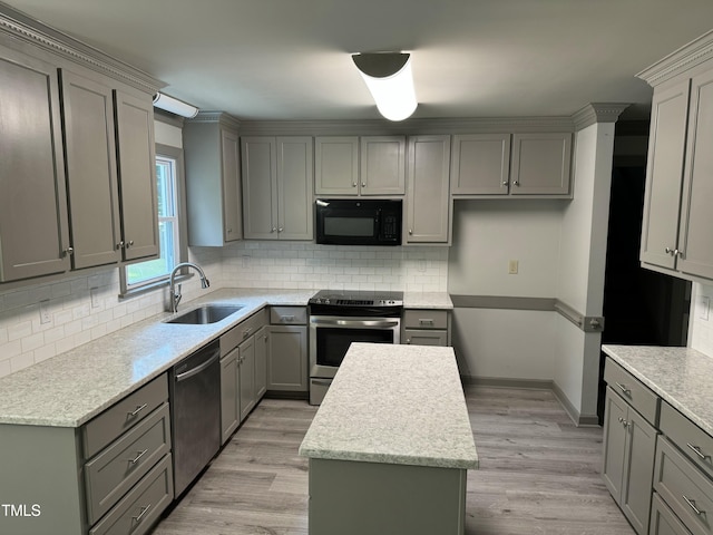 kitchen with gray cabinetry, sink, appliances with stainless steel finishes, and light hardwood / wood-style flooring