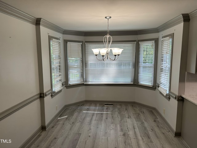 unfurnished dining area with a wealth of natural light, crown molding, and light wood-type flooring