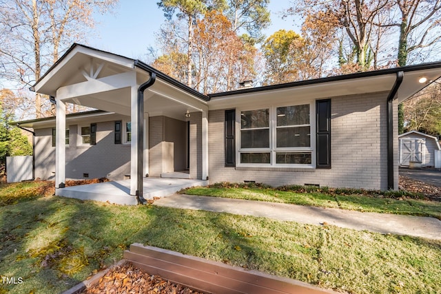 back of house with a lawn and a storage shed