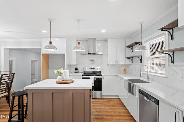 kitchen with pendant lighting, wall chimney range hood, light hardwood / wood-style floors, white cabinetry, and stainless steel appliances