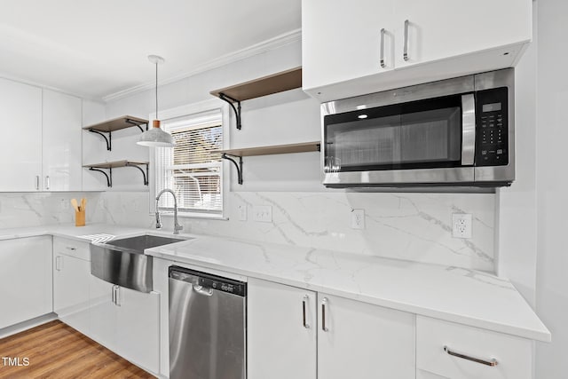 kitchen with light stone countertops, white cabinetry, sink, stainless steel appliances, and light wood-type flooring