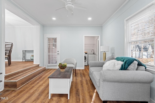 living room with washer / dryer, ornamental molding, dark wood-type flooring, and ceiling fan