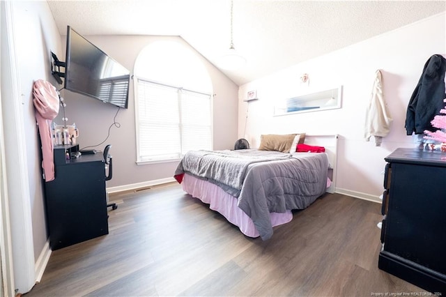 bedroom featuring dark hardwood / wood-style flooring, a textured ceiling, and vaulted ceiling