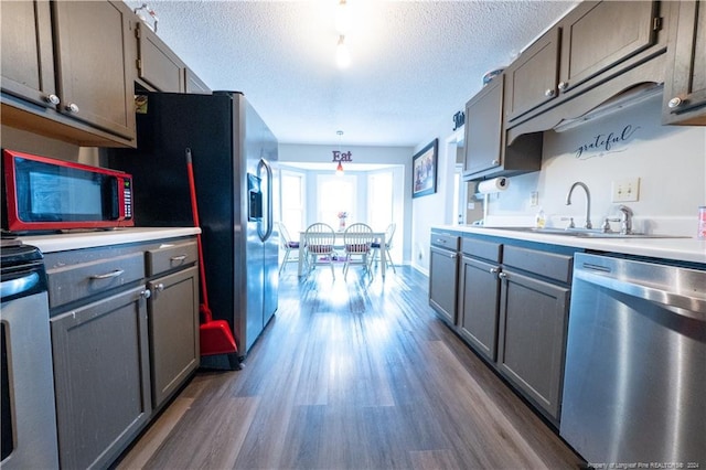 kitchen featuring sink, stainless steel appliances, dark hardwood / wood-style flooring, a textured ceiling, and gray cabinets