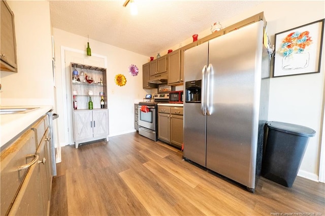 kitchen featuring sink, light hardwood / wood-style floors, a textured ceiling, and appliances with stainless steel finishes