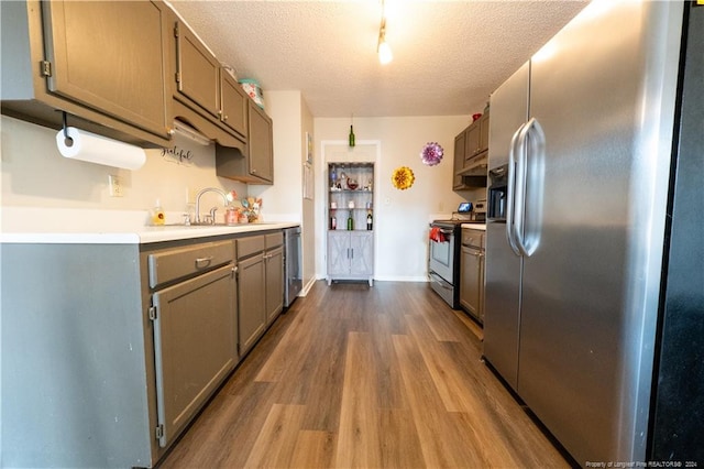 kitchen featuring light hardwood / wood-style flooring, stainless steel appliances, a textured ceiling, and sink