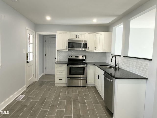 kitchen with sink, stainless steel appliances, tasteful backsplash, and white cabinetry