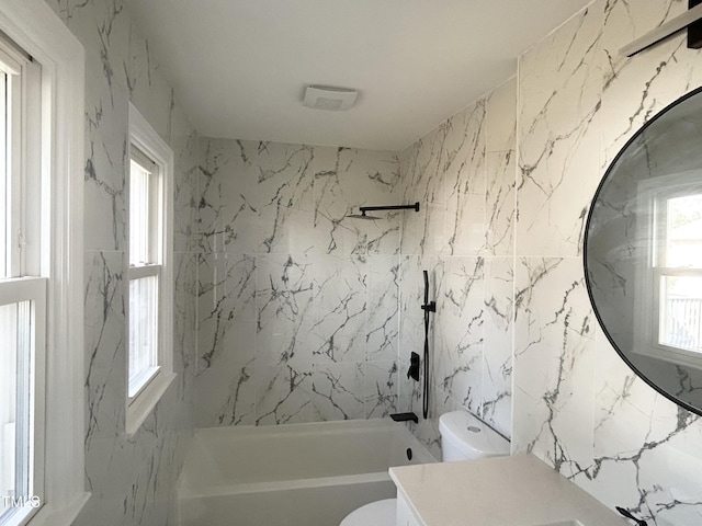 full bathroom featuring toilet, vanity, plenty of natural light, and tiled shower / bath