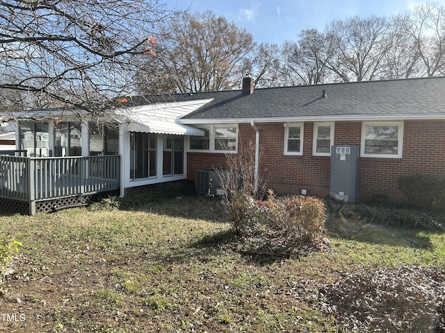 rear view of property with a yard, a deck, a sunroom, and central AC unit