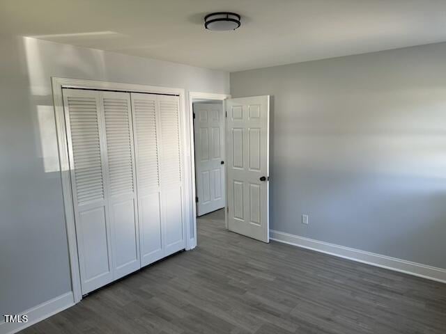 unfurnished bedroom featuring dark wood-type flooring and a closet