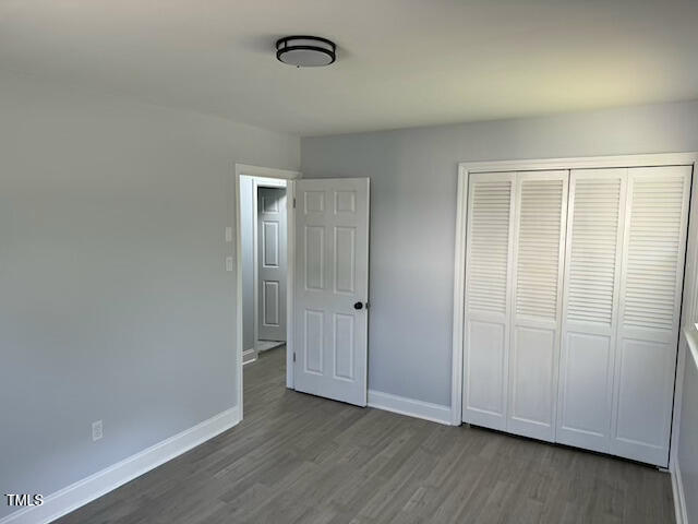 unfurnished bedroom featuring a closet and dark wood-type flooring