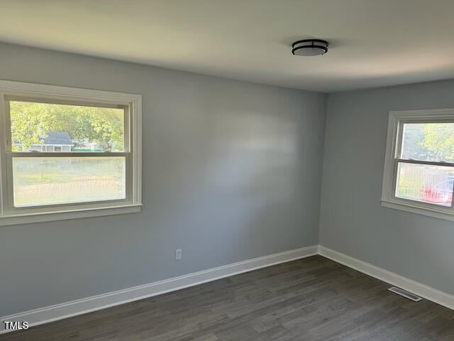 empty room with a healthy amount of sunlight and dark hardwood / wood-style floors