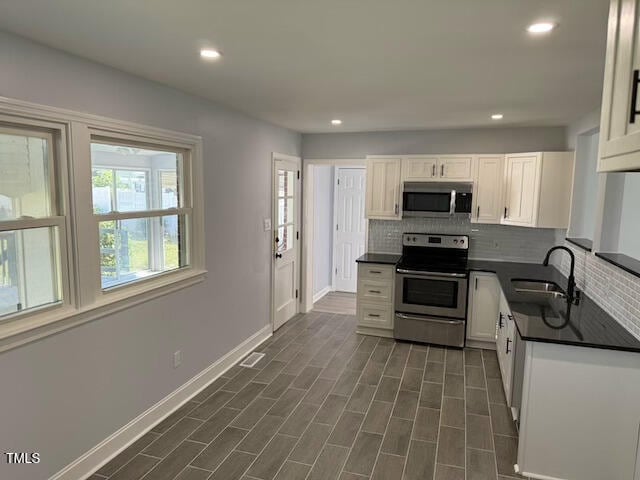 kitchen with white cabinets, appliances with stainless steel finishes, backsplash, and sink