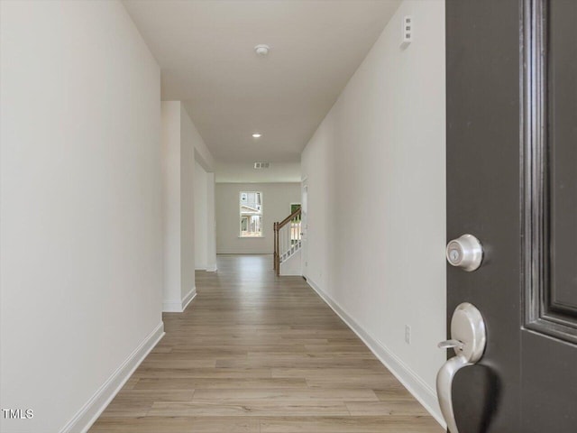 hallway featuring light wood-style flooring, visible vents, stairway, and baseboards