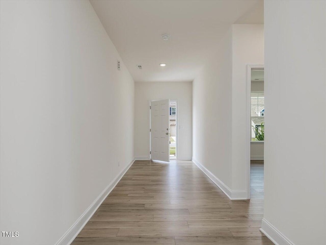 corridor with light wood finished floors and baseboards