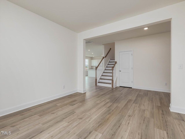 unfurnished room featuring light wood finished floors, baseboards, visible vents, stairway, and recessed lighting