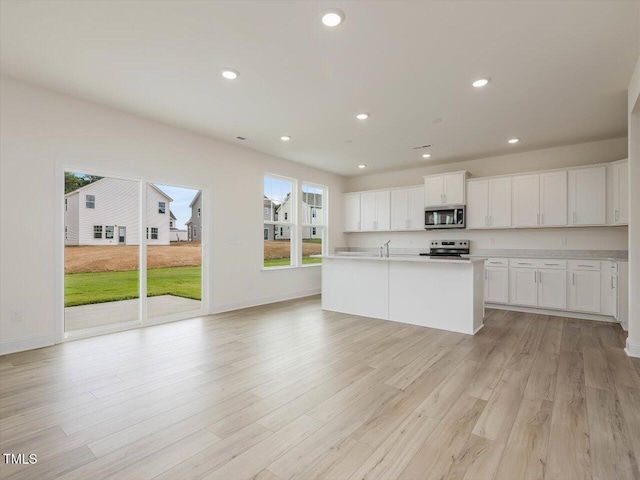 kitchen with stainless steel appliances, recessed lighting, light countertops, light wood-style floors, and white cabinetry