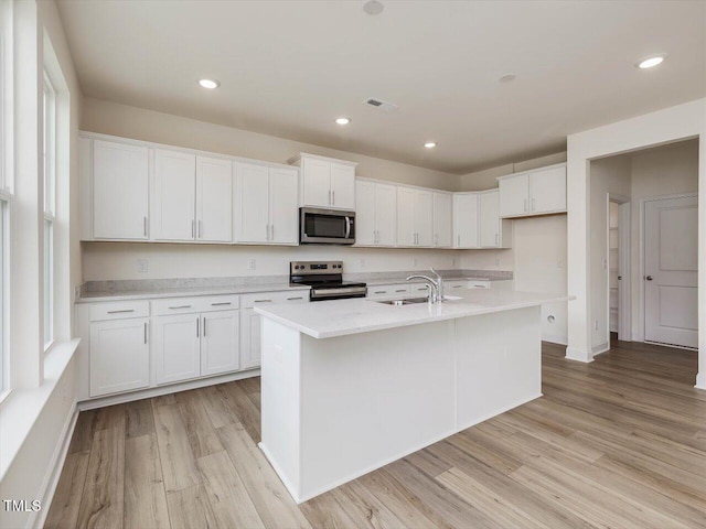 kitchen featuring light wood finished floors, visible vents, appliances with stainless steel finishes, white cabinetry, and a sink