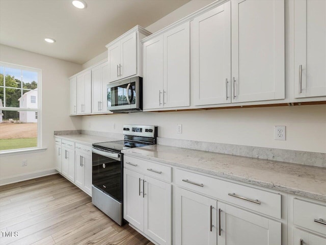 kitchen with baseboards, light wood-style flooring, appliances with stainless steel finishes, white cabinetry, and recessed lighting