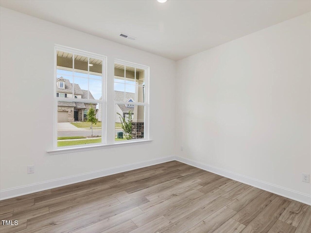 unfurnished room featuring wood finished floors, visible vents, and baseboards