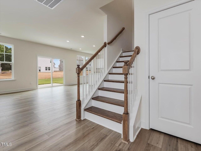 staircase with a healthy amount of sunlight, visible vents, wood finished floors, and recessed lighting