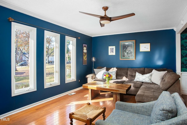 living room featuring hardwood / wood-style floors, a textured ceiling, ceiling fan, and ornamental molding