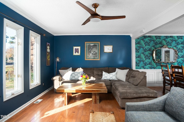 living room with a textured ceiling, hardwood / wood-style flooring, ceiling fan, and crown molding