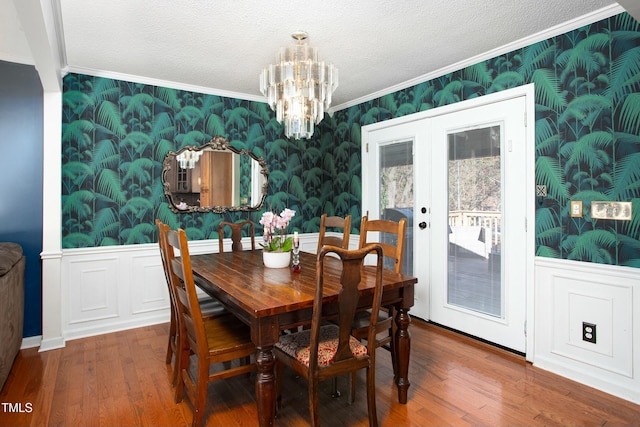 dining area featuring crown molding, french doors, an inviting chandelier, and hardwood / wood-style flooring