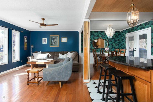 living room featuring french doors, ceiling fan, ornamental molding, a textured ceiling, and light hardwood / wood-style floors