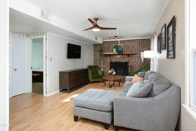 living room with a fireplace, light hardwood / wood-style floors, track lighting, and ceiling fan