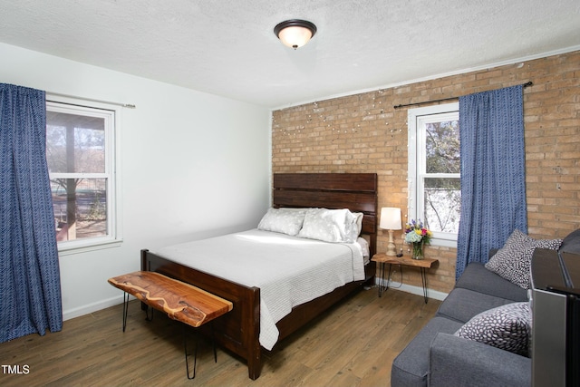 bedroom featuring a textured ceiling, dark wood-type flooring, and brick wall