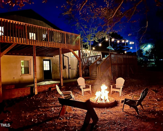 patio at night featuring a fire pit and a wooden deck