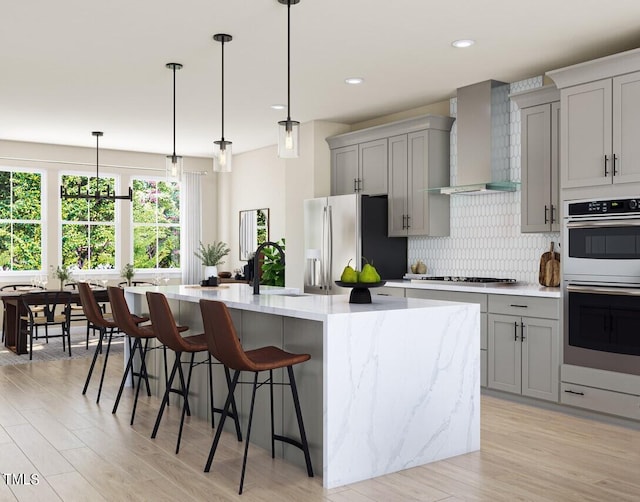 kitchen with tasteful backsplash, wall chimney exhaust hood, stainless steel appliances, and gray cabinetry