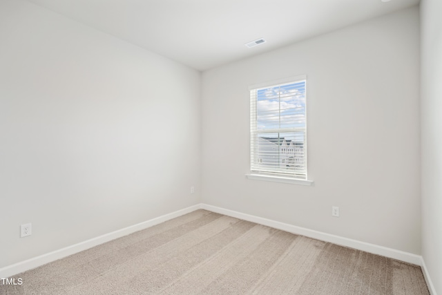 unfurnished room with light carpet, visible vents, and baseboards