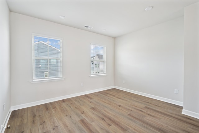 empty room with visible vents, baseboards, and wood finished floors