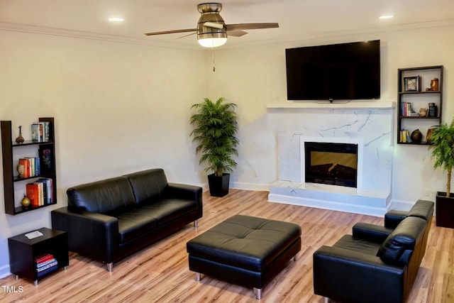 living area with ornamental molding, wood finished floors, and a high end fireplace