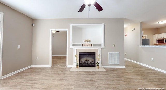 unfurnished living room with a fireplace, wood finished floors, visible vents, and baseboards