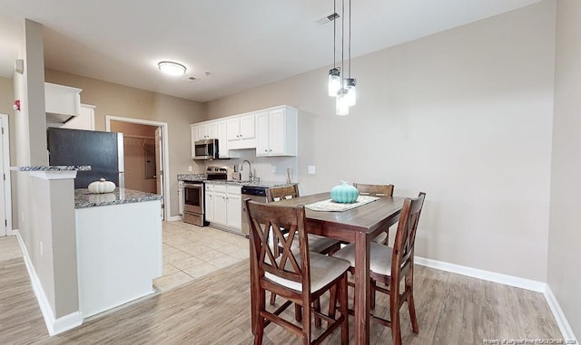 dining room with light wood-style floors, visible vents, and baseboards