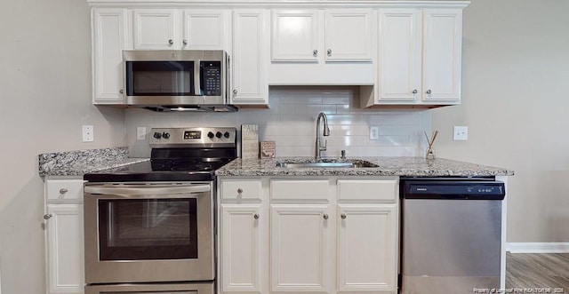 kitchen featuring appliances with stainless steel finishes, a sink, white cabinets, and decorative backsplash