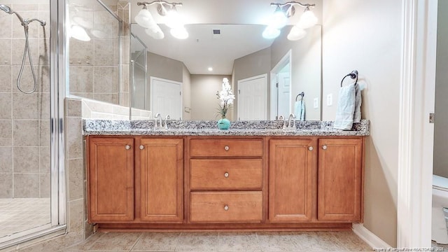 full bathroom featuring double vanity, a stall shower, tile patterned flooring, and a sink