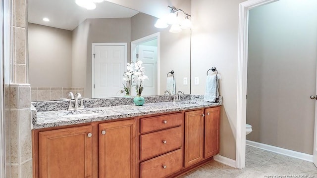 full bathroom featuring double vanity, tile patterned flooring, toilet, and a sink