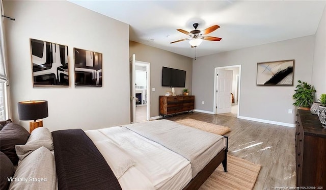 bedroom with a ceiling fan, ensuite bathroom, baseboards, and wood finished floors