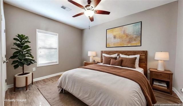 bedroom featuring ceiling fan, wood finished floors, visible vents, and baseboards