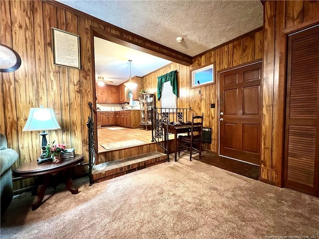 entryway featuring beam ceiling, ceiling fan, carpet, and a textured ceiling