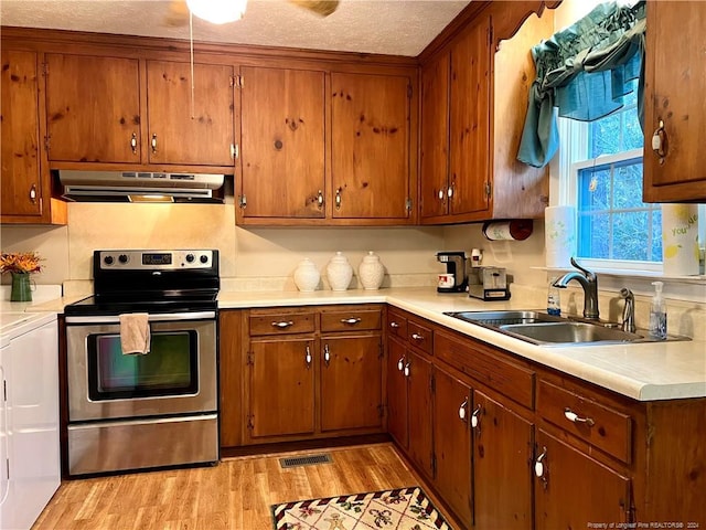 kitchen with a textured ceiling, washer / clothes dryer, sink, electric range, and light hardwood / wood-style floors