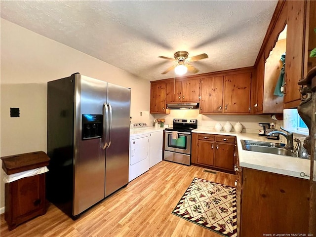 kitchen with sink, stainless steel appliances, light hardwood / wood-style floors, a textured ceiling, and washer and clothes dryer