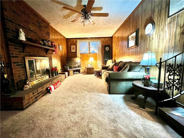 carpeted living room featuring a textured ceiling, a brick fireplace, ceiling fan, and wood walls