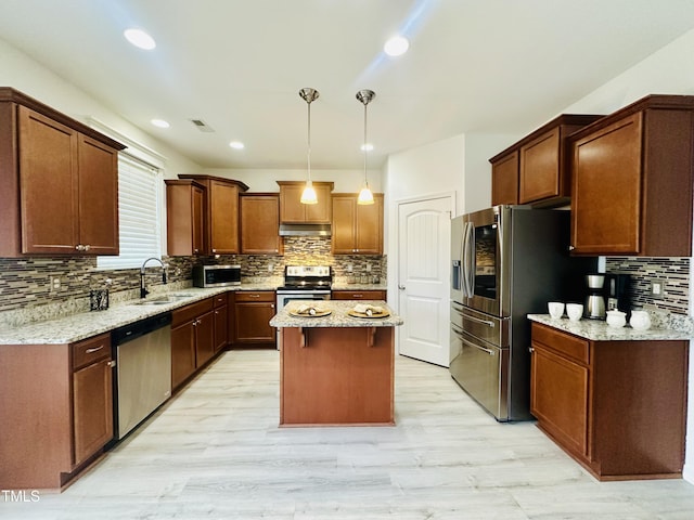 kitchen with light stone countertops, sink, a center island, and stainless steel appliances